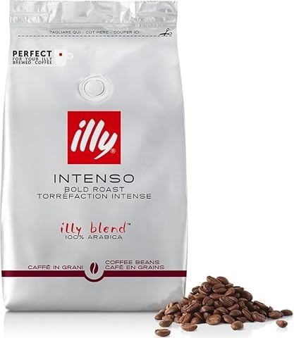 Grains de café Illy Intenso dans un contenant ouvert, posés sur un plan de travail en bois brun.