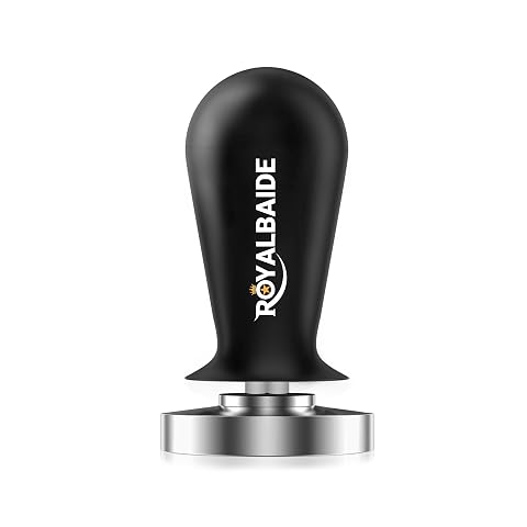Tasseur expresso à ressort en inox et aluminium posé près de grains de café sur un plan de travail en bois