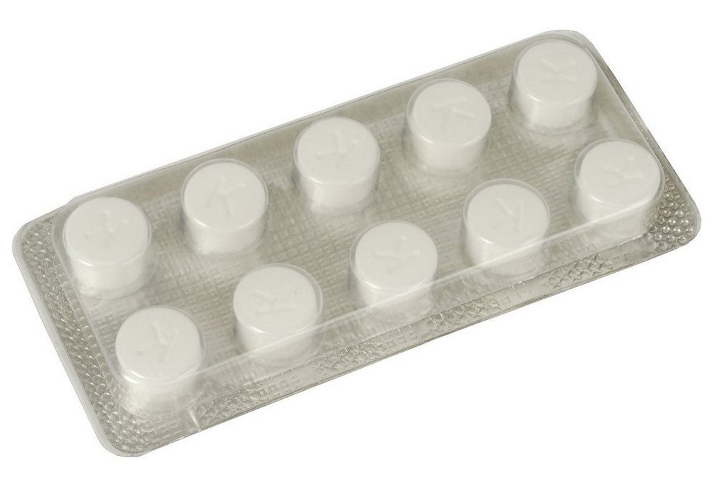 Dix pastilles nettoyantes Krups disposées en deux rangées sur un plan de travail en bois