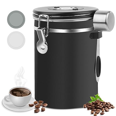 Boîte à café noire en acier inoxydable avec cadran de date et cuillère doseuse sur un plan de travail.