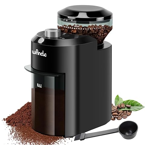 Moulin à café électrique compact noir et gris posé sur un plan de travail en bois avec quelques grains