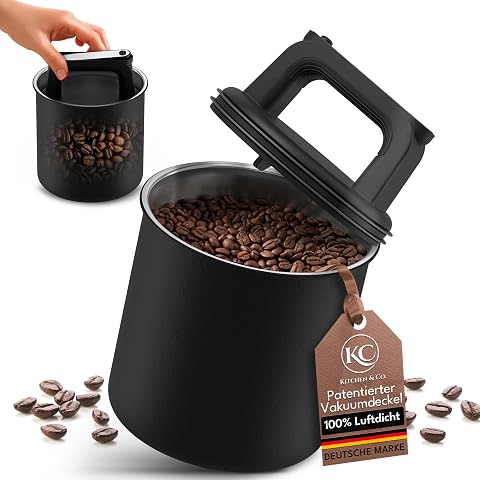 Boîte à café noire en acier inoxydable avec couvercle sous vide, posée près de grains